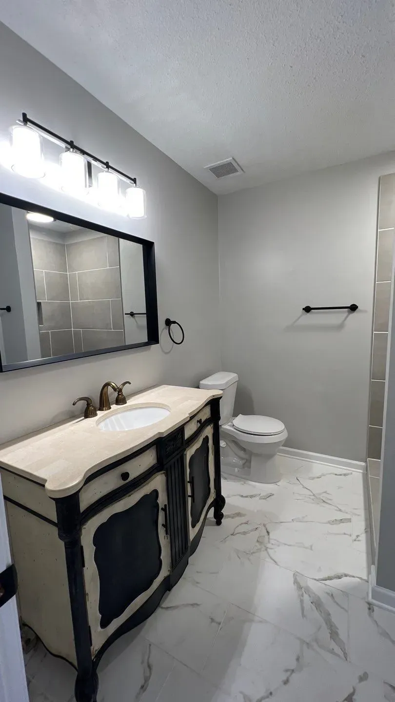 Matser bath renovation featuring marble floor tile and classic style vanity.