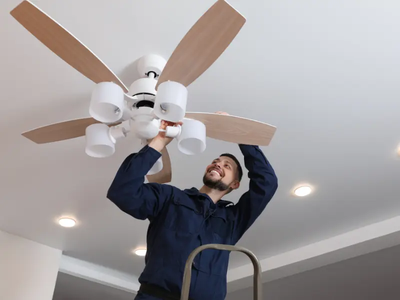 Man performing maintenance on a fan.