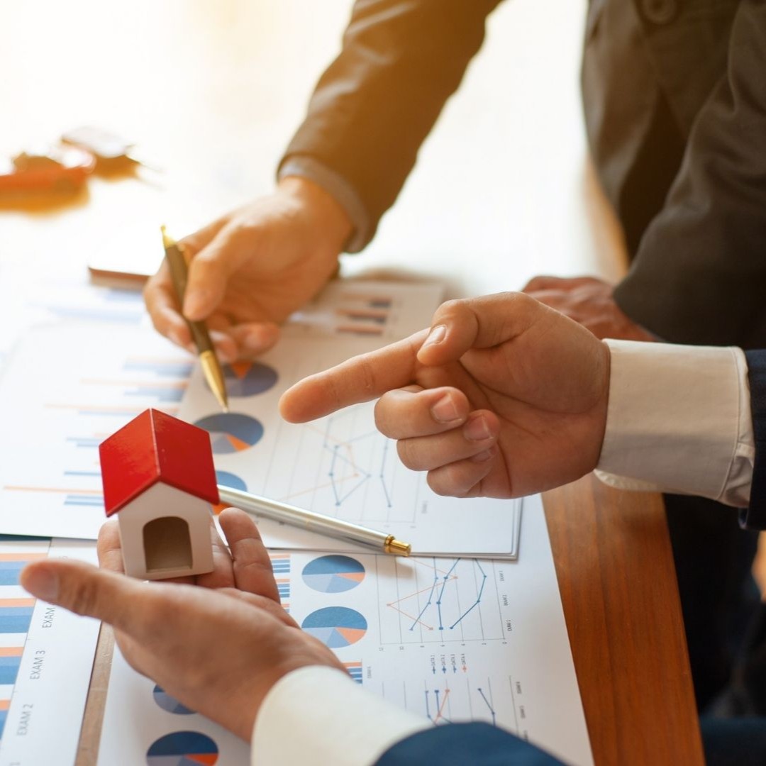 Property managers reviewing rental documents and house model during Olive Branch rental marketing strategy meeting