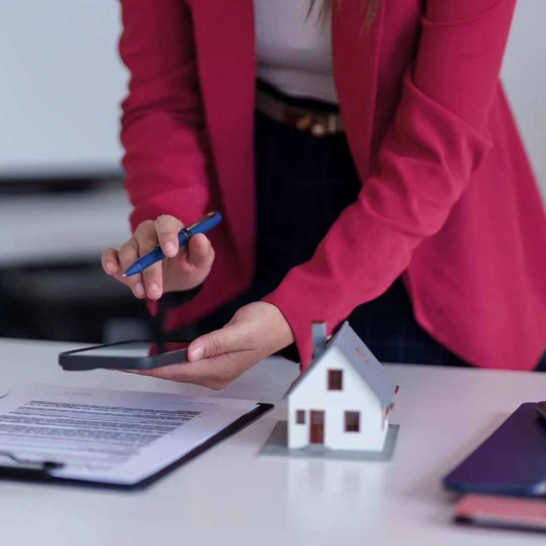Property manager reviewing BRRRR rehab scope and budget paperwork with a house model and calculator for a Memphis, TN investment property.