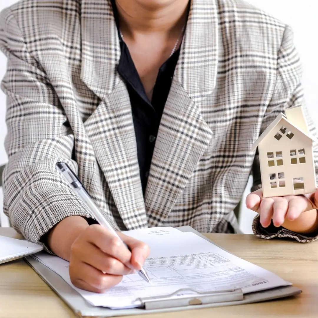Investor reviewing BRRRR acquisition paperwork with a house model and piggy bank in Collierville, TN.