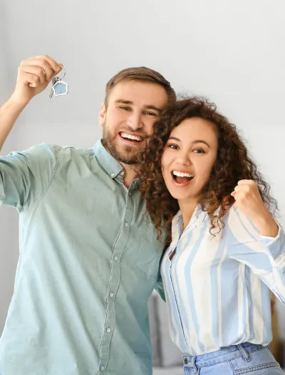 Couple cheering with house keys in hand.