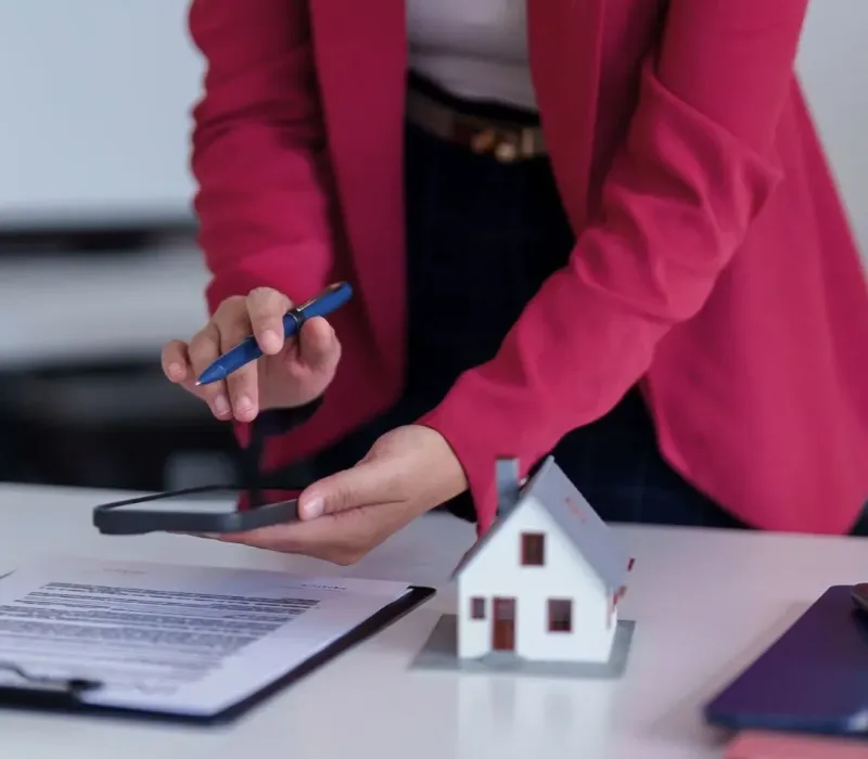Property manager reviewing BRRRR rehab scope and budget paperwork with a house model and calculator for a Memphis, TN investment property.