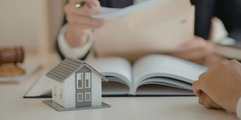 Property manager reviewing BRRRR acquisition documents with a home model on the table representing investment property consultation in Eads, TN