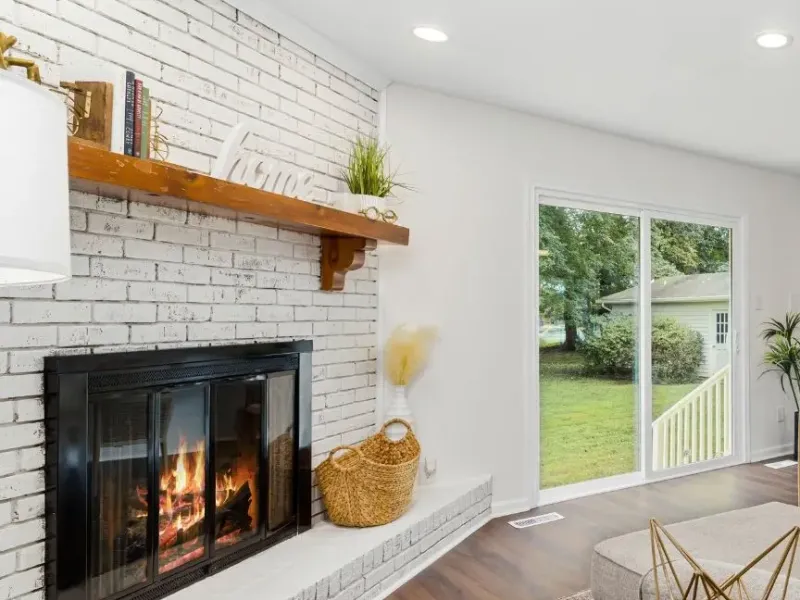 Property management renovation in Nesbit MS living room with painted brick fireplace, wood mantel, and backyard view.