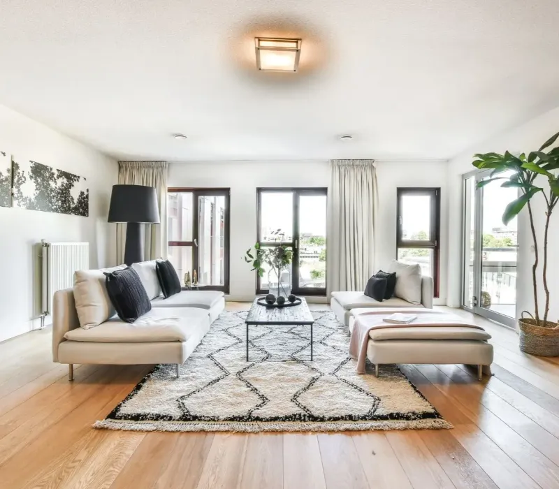 Renovated Nesbit MS rental living room with light sofas, large windows, and hardwood floors.