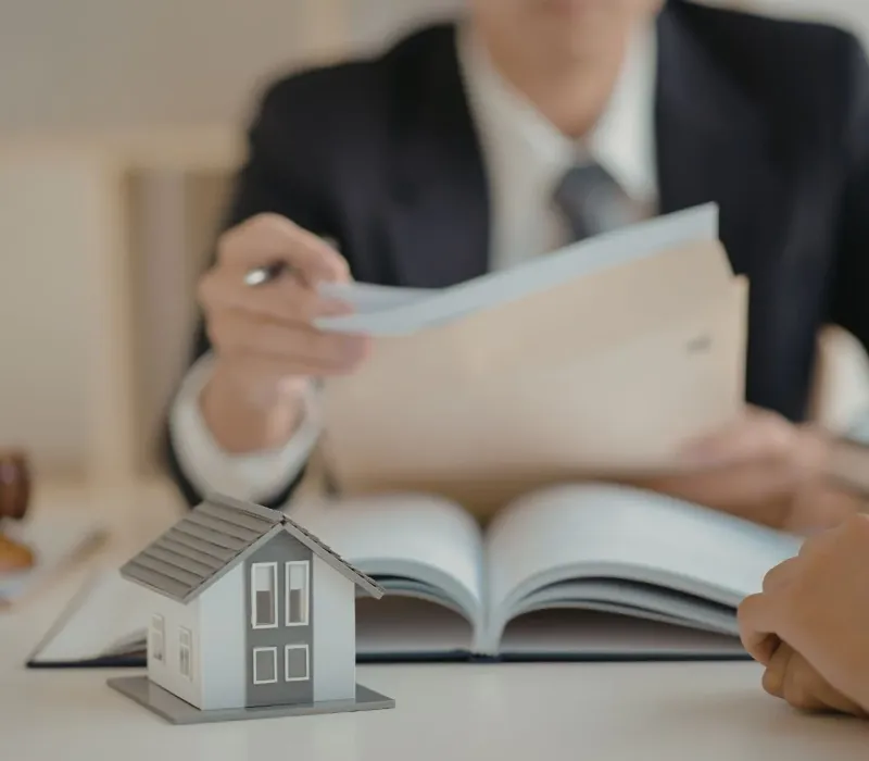 Property manager reviewing BRRRR acquisition documents with a home model on the table representing investment property consultation in Eads, TN