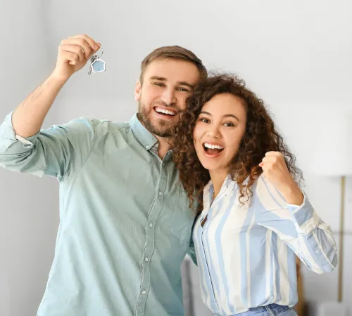 Couple cheering with house keys in hand.