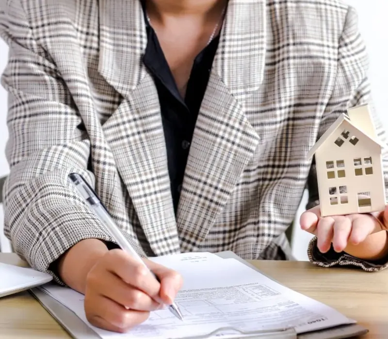 Investor reviewing BRRRR acquisition paperwork with a house model and piggy bank in Collierville, TN.