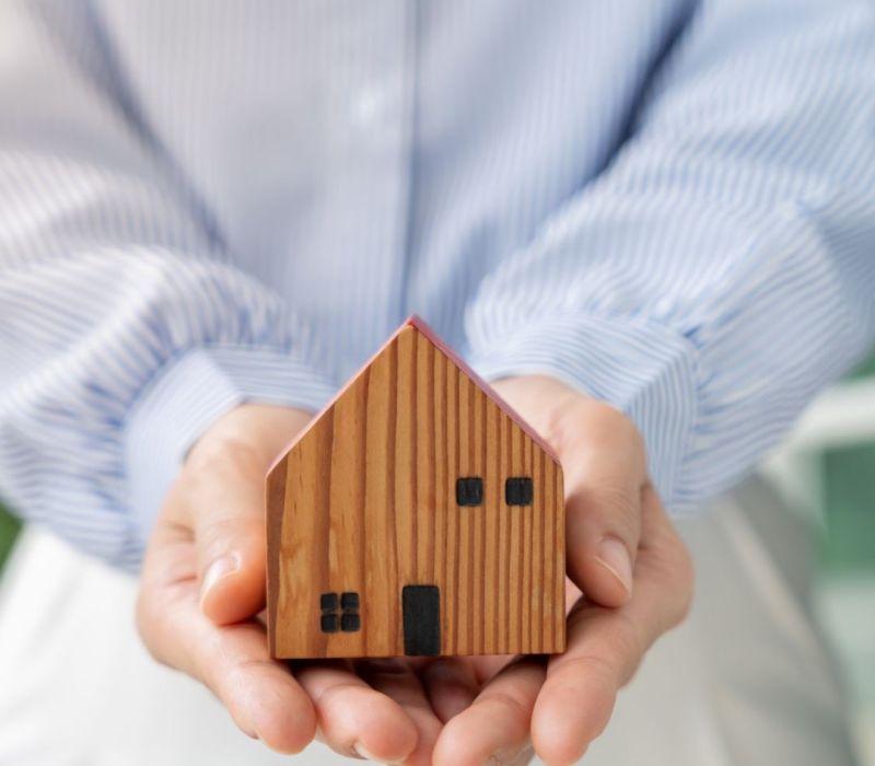 Property manager holding a home model representing BRRRR acquisition support and investment property management in Lakeland, TN