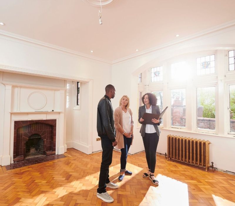 Property manager conducting walkthrough of a renovated Cordova, TN rental with parquet floors, fireplace, and bright windows