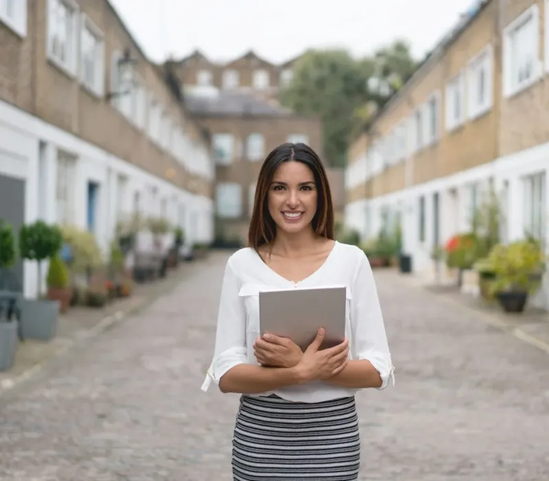Real estate agent holding a tablet in front of rental properties representing BRRRR investment opportunities and agent partnership in Eads, TN