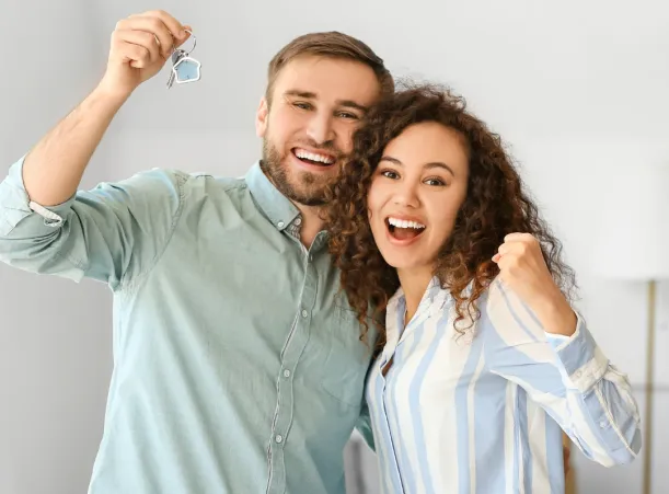 Couple cheering with house keys in hand.