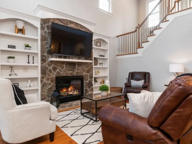 Updated living room with stone fireplace, built-in shelving, and staged seating after property management renovation in Byhalia, MS.