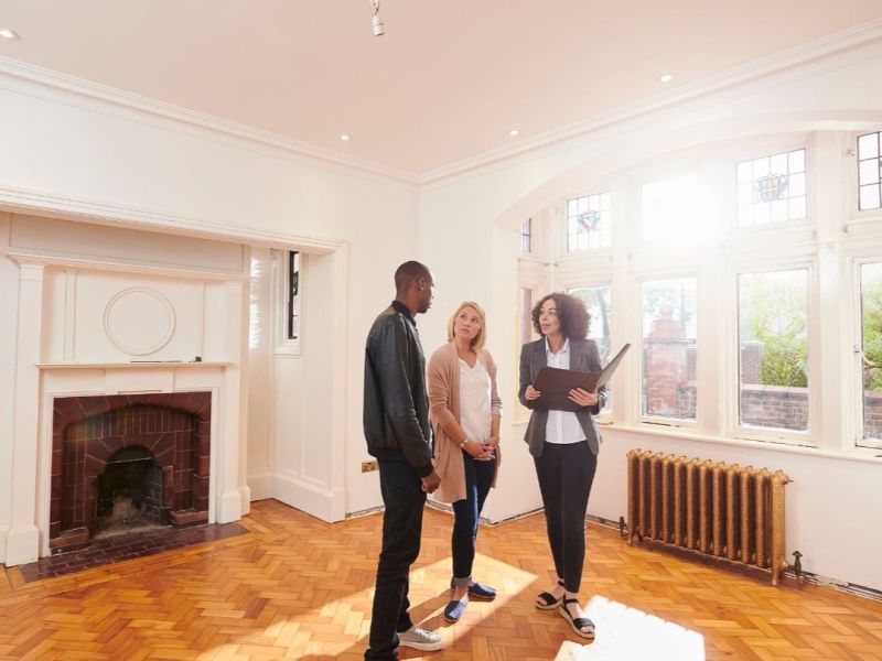 Property manager conducting walkthrough of a renovated Cordova, TN rental with parquet floors, fireplace, and bright windows